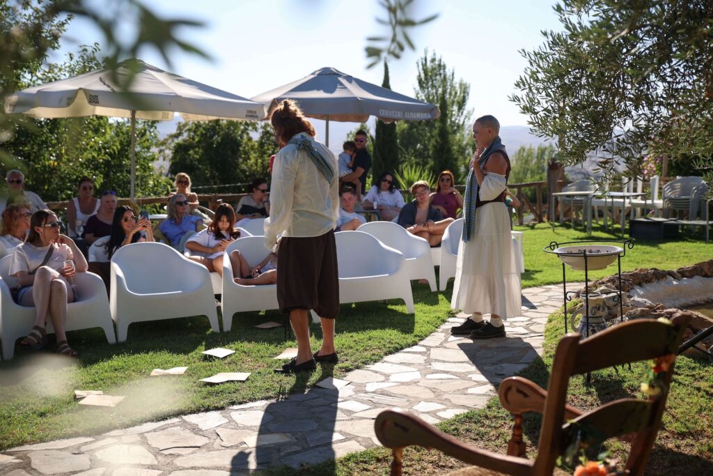 Actors performing among the audience during an outdoor Two Roots Theatre show